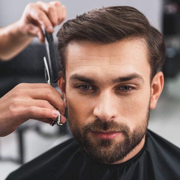 Confident young man is getting haircut at beauty salon